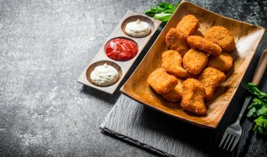 Maydanoz ve farklı soslar ile tavuk nuggets. Koyu rustik arka plan üzerinde
