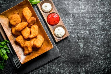 Maydanoz ve farklı soslar ile tavuk nuggets. Koyu rustik arka plan üzerinde