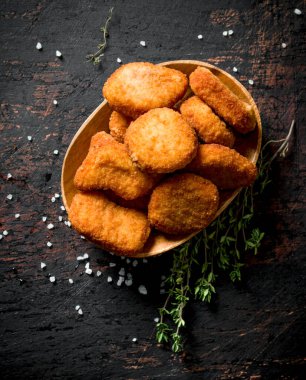 Kekikli bir kapta tavuk külçeleri. Koyu rustik arka plan üzerinde