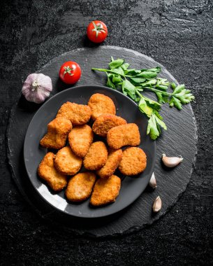 Maydanoz ve sarımsak karanfil ile tavuk nuggets. Siyah rustik arka plan üzerinde