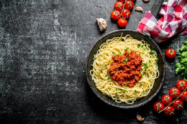 Bir peçete ve domates ile tavada Bolonya soslu Spagetti. Rustik arka planda