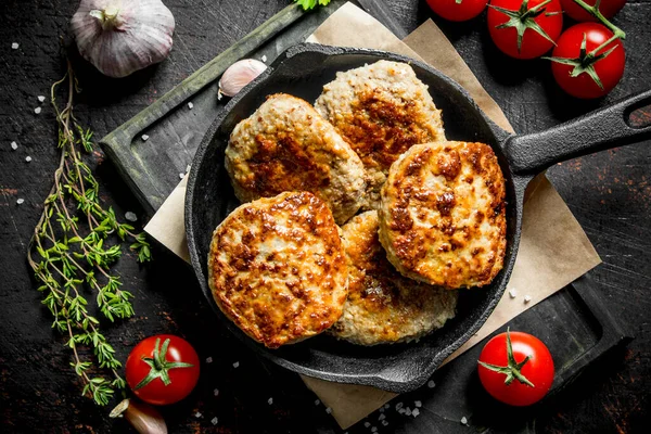 stock image Cutlets in pan with thyme,garlic and tomatoes. On rustic background