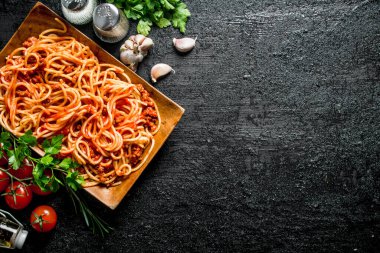 Otlar, domates ve sarımsak ile bir tabakta Bolonya soslu Spagetti. Rustik arka planda