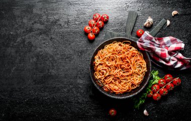 Peçete, domates ve sarımsak ile tavada Bolonya soslu Spagetti. Siyah rustik arka plan üzerinde