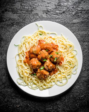 Tabakta et topları olan spagetti. Siyah rustik arka plan üzerinde