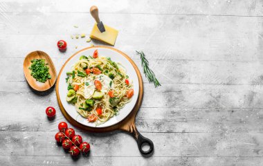 Bir kase, domates ve Parmesan peyniri doğranmış yeşillik ile Sebze makarna. Beyaz ahşap arka plan üzerinde