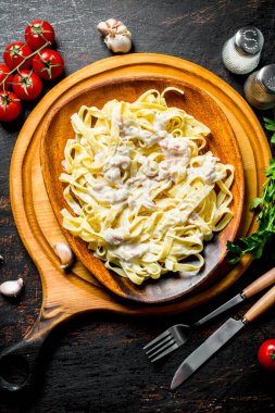 Bir tabakta Carbonara soslu makarna fettuccine ve baharatlı domates. Rustik arka planda