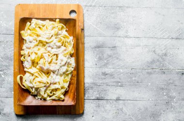 Tahta bir tabakta Carbonara soslu fettuccine. Beyaz ahşap arka plan üzerinde