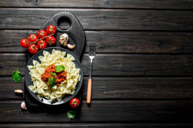 Domates, sarımsak ve nane yaprakları ile Bolonya soslu Farfalle makarna. Siyah ahşap arka plan üzerinde