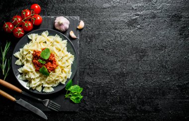 Domates, biberiye ve sarımsak ile Farfalle makarna. Siyah rustik arka plan üzerinde