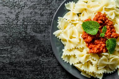 Bolonya soslu ve nane yaprakları ile Farfalle makarna. Rustik arka planda