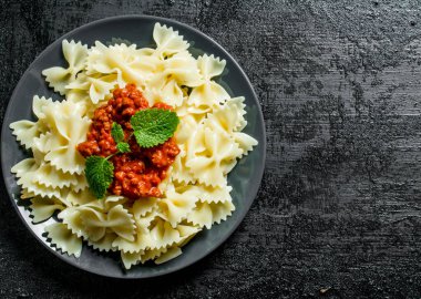 Bolonya soslu ve nane yaprakları ile Farfalle makarna. Rustik arka planda