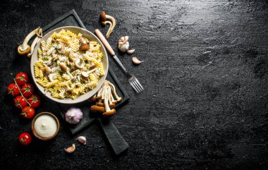 Mantar, domates ve kase sos ile Fusilli makarna. Siyah rustik arka plan üzerinde