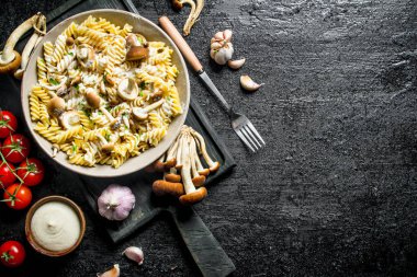 Mantar, domates ve sarımsak ile Fusilli makarna. Siyah rustik arka plan üzerinde