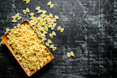 Bir tabakta Kuru Farfalle makarna. Koyu rustik arka plan üzerinde