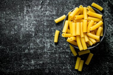 Bir kasede kuru makarna. Siyah rustik arka plan üzerinde