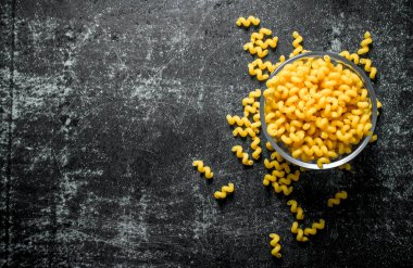 Bir kasede kuru makarna. Siyah rustik arka plan üzerinde