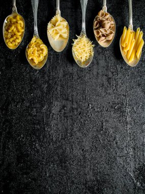 Kaşıkkuru makarna farklı türleri. Siyah rustik arka plan üzerinde