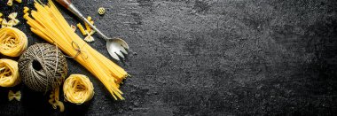 Kuru makarna tagliatelle ve spagetti ip ile. Siyah rustik arka plan üzerinde