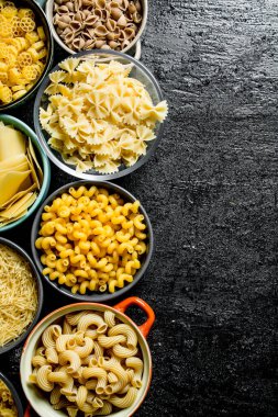 Kaselerde kuru makarna farklı türleri. Siyah rustik arka plan üzerinde