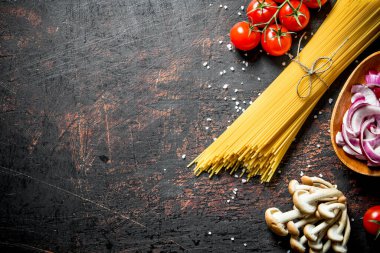Domates, mantar ve kase soğan kesme ile çiğ spagetti. Rustik arka planda