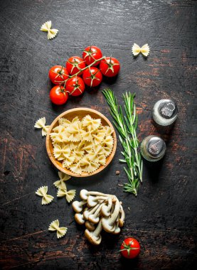 Domates, biberiye, mantar ve baharat ile bir kapta Çiğ Farfalle makarna. Rustik arka planda