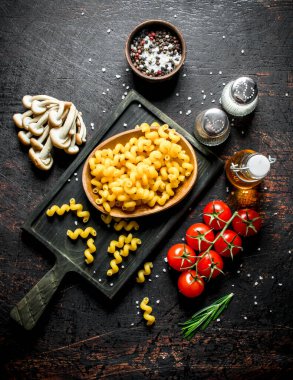 Mantar, domates ve baharat ile kase çiğ makarna. Koyu rustik arka plan üzerinde