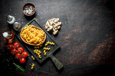 Mantar, domates ve baharat ile kase çiğ makarna. Koyu rustik arka plan üzerinde