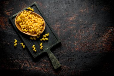 Kesme Tahtası üzerinde bir kase de çiğ makarna. Rustik arka planda