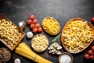 Mantar, domates ve sarımsak ile çiğ makarna farklı çeşitleri. Koyu rustik arka plan üzerinde