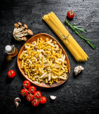 Biberiye, domates ve mantar ile çiğ makarna çeşitleri. Siyah rustik arka plan üzerinde