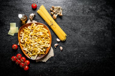 Peynir dilimleri, mantar ve domates ile çiğ makarna farklı türleri. Siyah rustik arka plan üzerinde