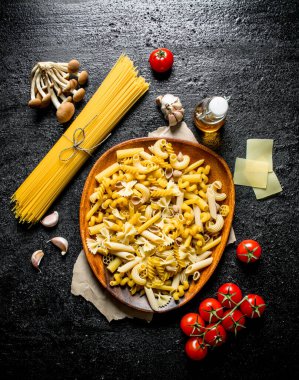 Mantar ve domates ile çiğ makarna farklı türleri. Siyah rustik arka plan üzerinde