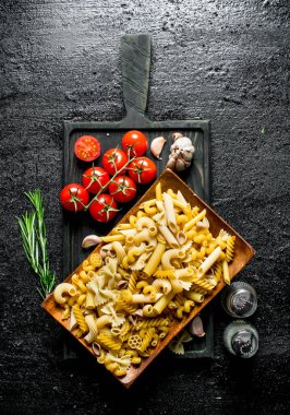 Domates, sarımsak ve biberiye ile bir tabakta çiğ salça farklı türde. Siyah rustik arka plan üzerinde