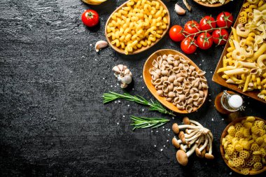 Mantar, biberiye ve domates ile kaselerde çiğ hamur farklı türleri. Siyah rustik arka plan üzerinde