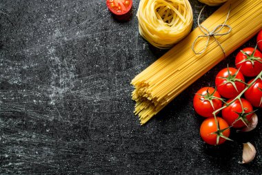 Spagetti ve tagliatelle sarımsak karanfil ve domates ile çiğ. Rustik arka planda