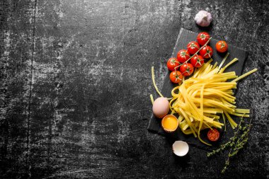 Bir taş Tahta üzerinde yumurta, domates ve sarımsak ile ev yapımı çiğ makarna. Rustik arka planda