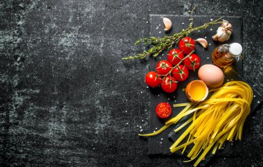 Kekik, yumurta, yağ ve domates ile ev yapımı çiğ makarna. Siyah rustik arka plan üzerinde