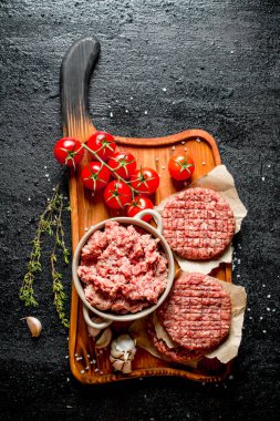 Çiğ hamburger ve domates, sarımsak karanfil ve kekik ile kıyma. Rustik arka planda
