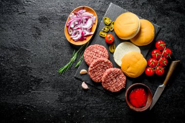 Çiğ hamburger. Sığır burger köftesi pişirme. Siyah rustik arka plan üzerinde