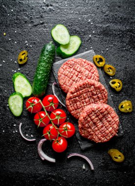 Jalapeno biber, domates ve salatalık ile çiğ burger. Siyah rustik arka plan üzerinde