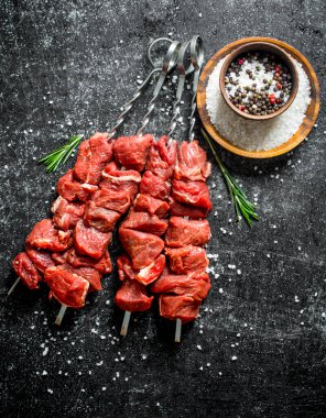 Kaseve biberiye baharat ile çiğ kebap. Siyah rustik arka plan üzerinde