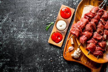 Sarımsak karanfil ve çeşitli soslar ile bir tabakta çiğ sığır kebap. Rustik arka planda