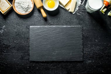 Pişirme arka plan. Yumurta, tereyağı, bal ve süt ile un. Siyah rustik arka plan üzerinde