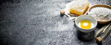 Bal, yumurta ve sivri ile un. Siyah rustik arka plan üzerinde