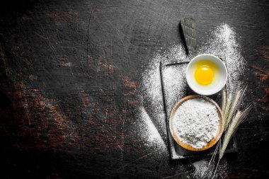 Kesme Tahtası üzerinde yumurta ve sivri ile un. Koyu rustik arka plan üzerinde