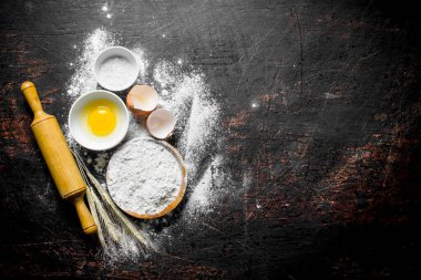 Yumurtalı un ve oklava. Koyu rustik arka plan üzerinde