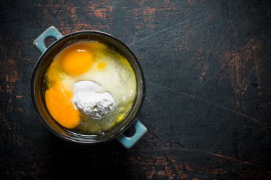 Tavada yumurta ile un. Koyu rustik arka plan üzerinde