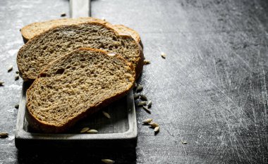 Kesme Tahtasında tahıllı ekmek parçaları. Koyu rustik arka plan üzerinde