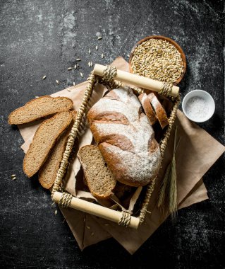 Tahıl ve tuz ile bir sepet içinde ekmek parçaları. Koyu rustik arka plan üzerinde